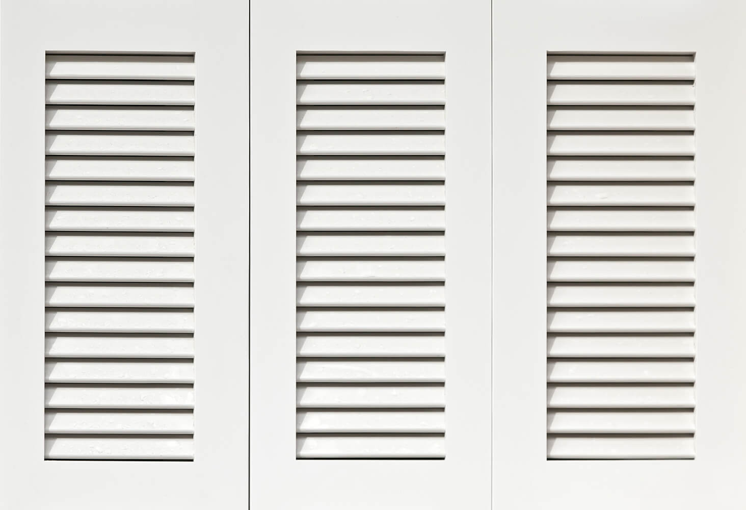 Three white cabinet doors with horizontal slats on a white background